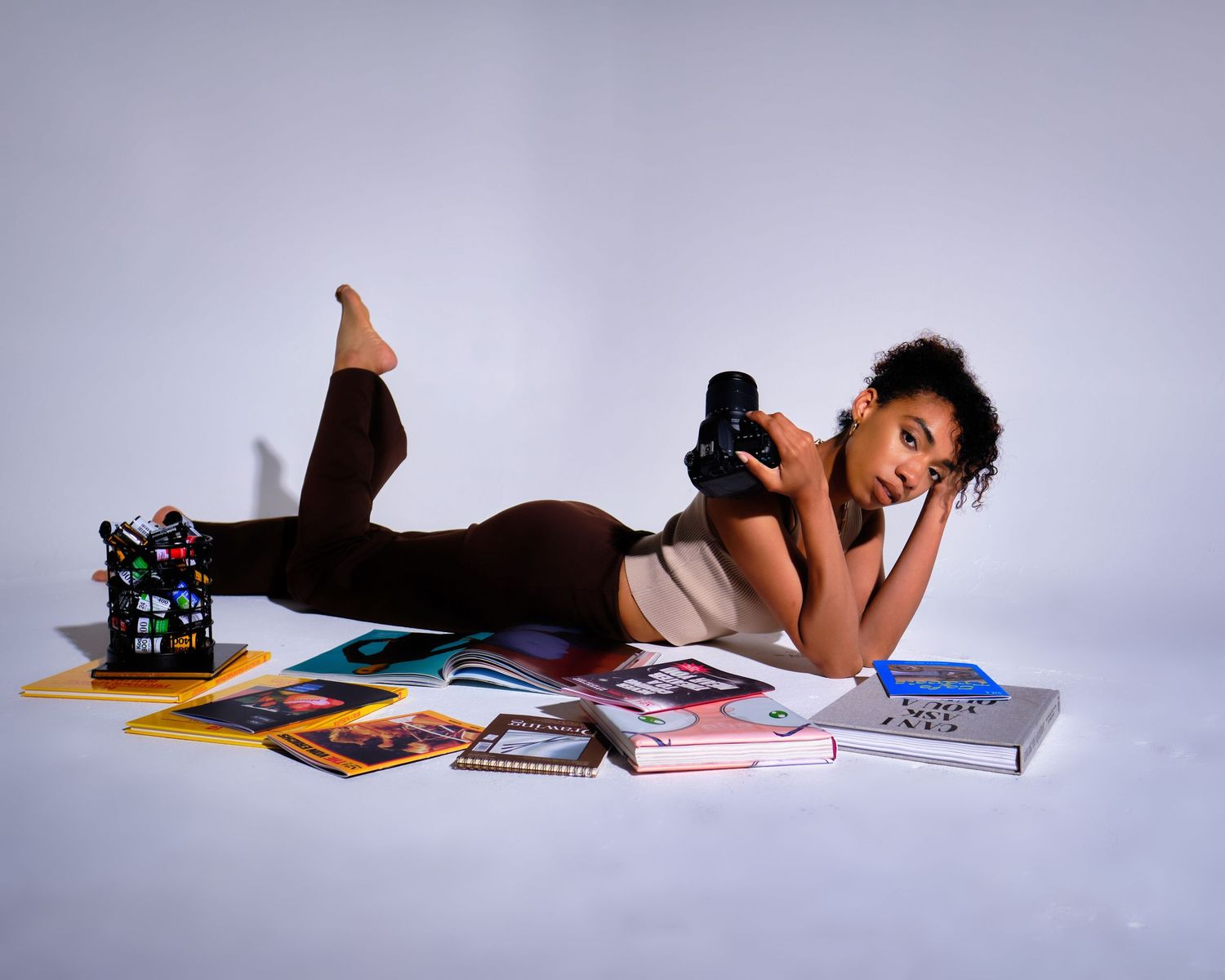 Person relaxing on floor surrounded by magazines and records.