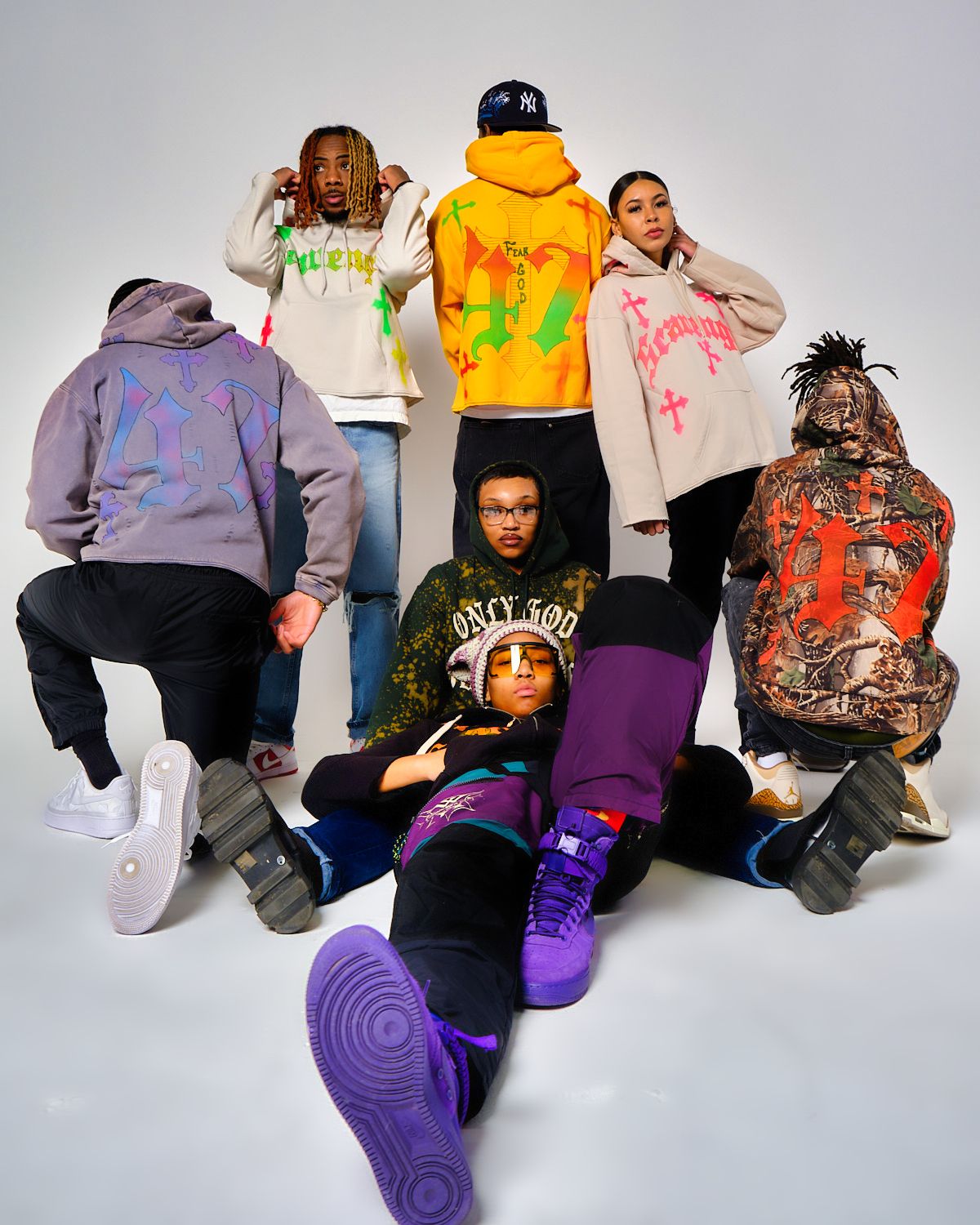 Group photo of people in colorful hoodies posing together in studio setting.