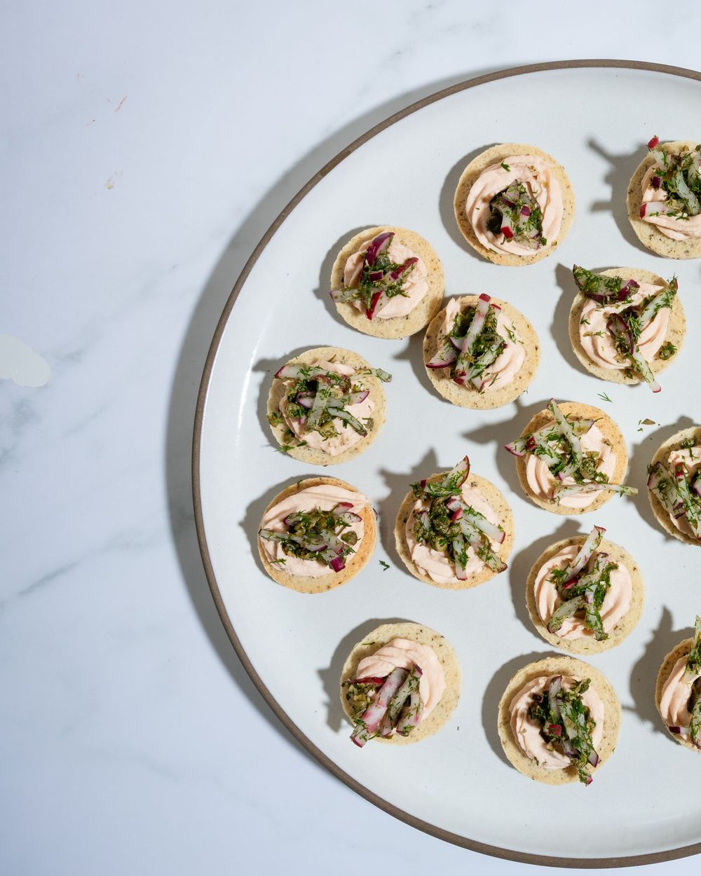 A white plate holding several mushroom and herb pinwheel appetizers arranged in a circular pattern.