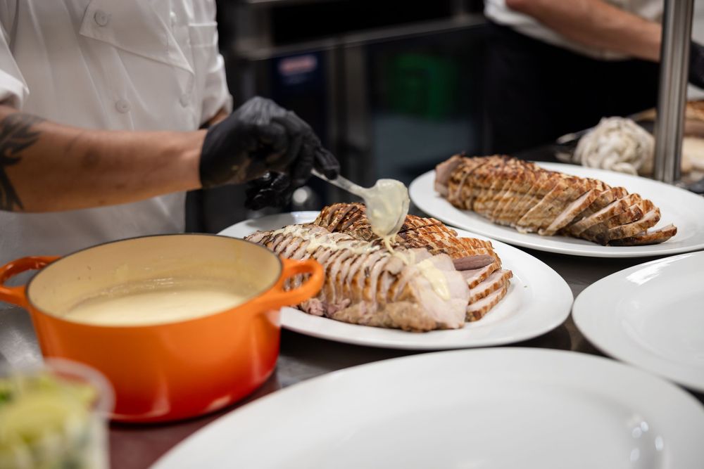 A warm pot of cheese fondue sits beside sliced bread on white plates in a restaurant setting.
