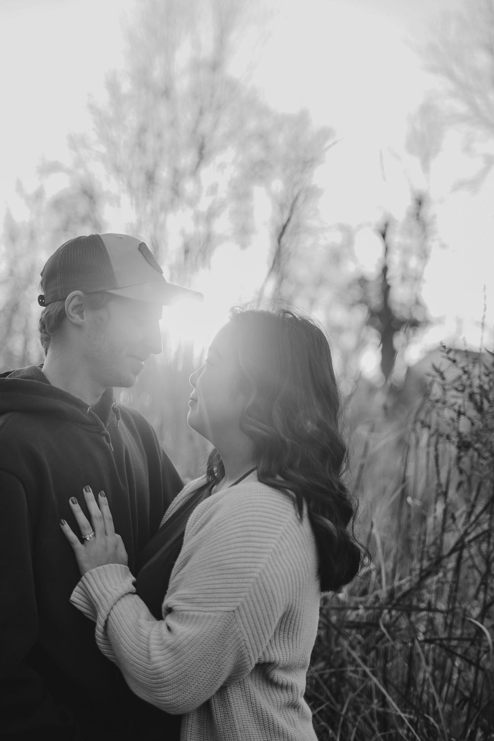 Romantic silhouette of couple embracing against misty natural backdrop.