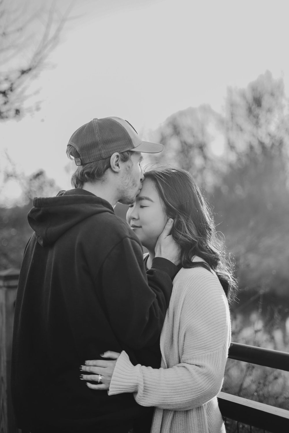 Couple sharing intimate moment outdoors in black and white photography.