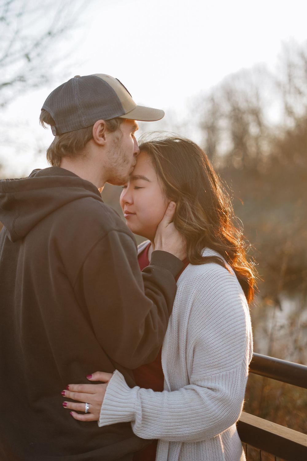 Couple in casual winter attire embracing during sunset photoshoot.