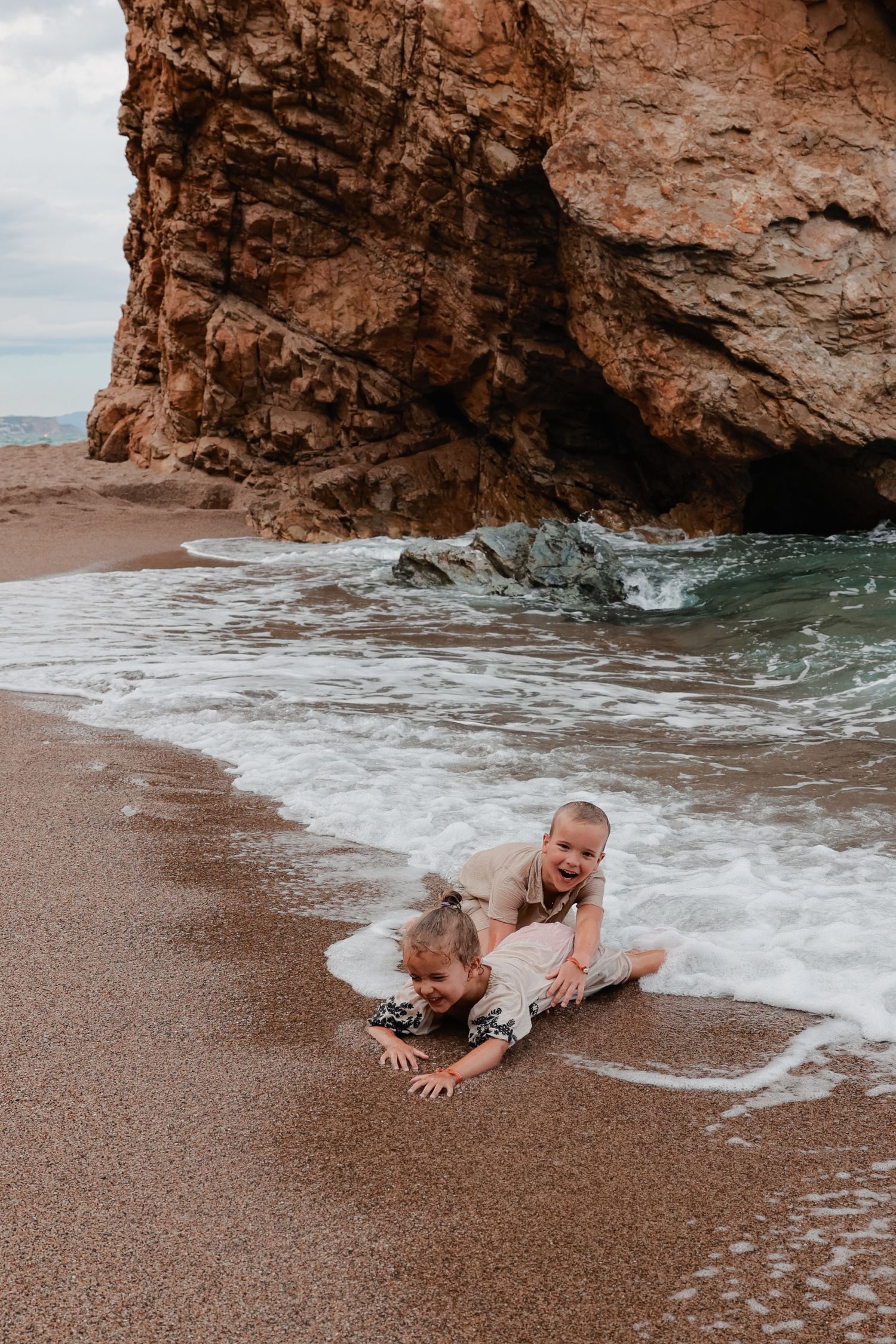 A sequence of playful photos showing someone getting splashed by ocean waves on a rocky beach.