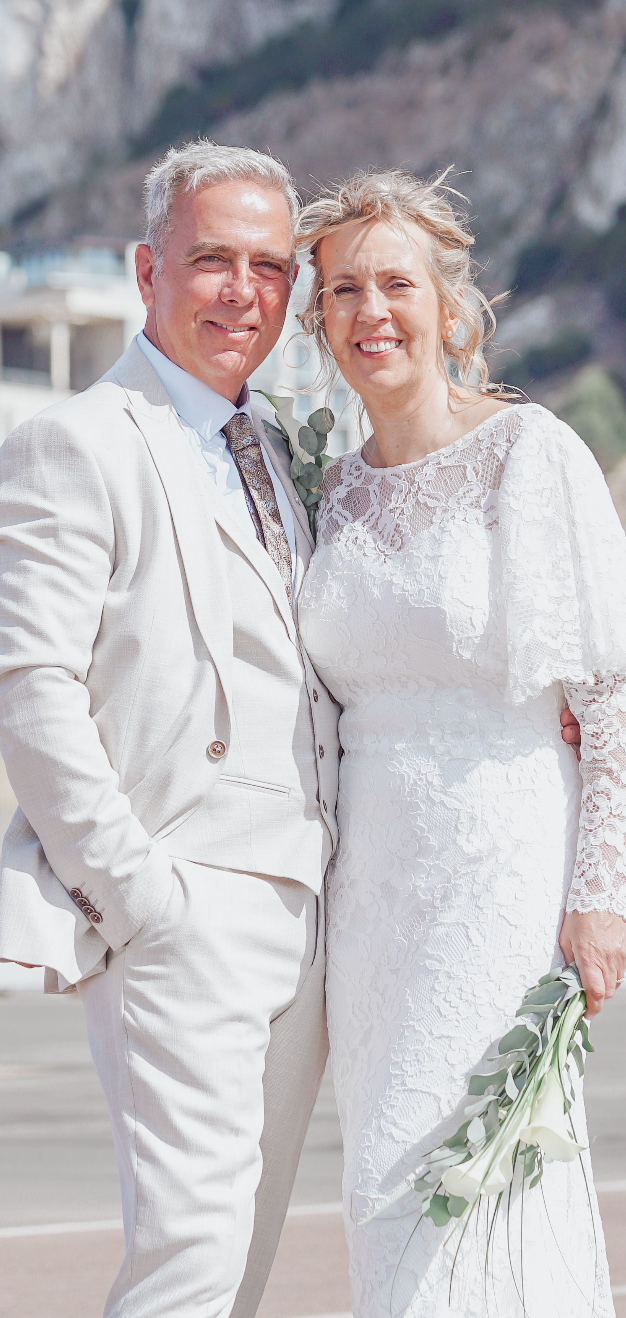 Bride and groom looking at camera in embrace on runway at Gibraltar Airport