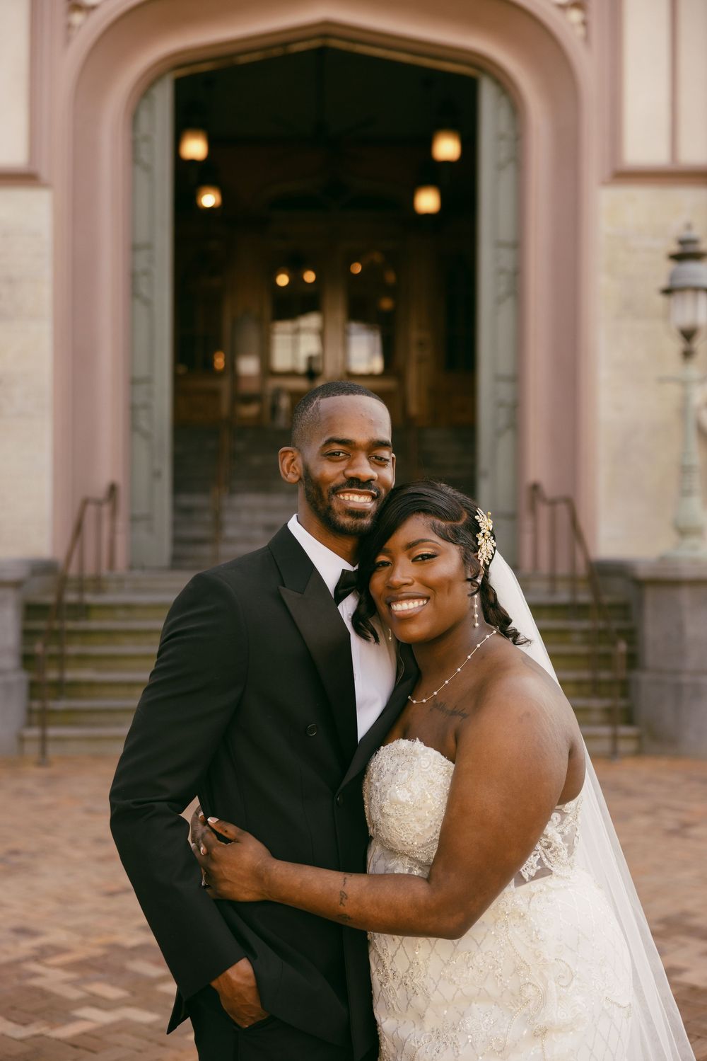 A joyful couple shares a romantic moment outside a grand building on their wedding day.