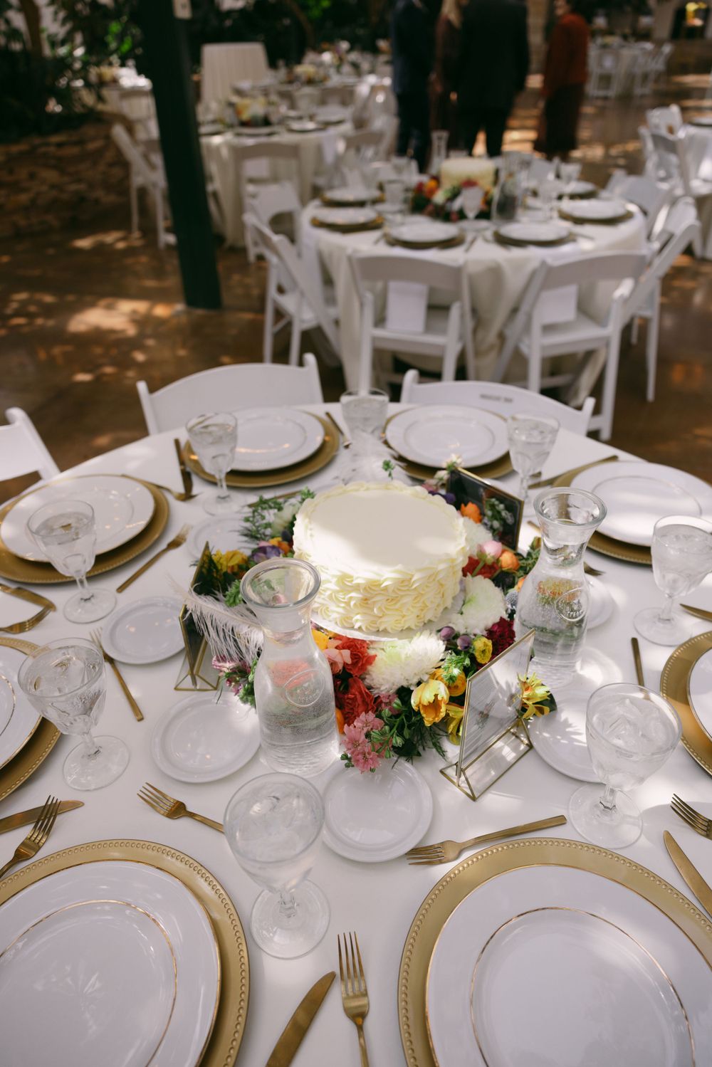 Elegant wedding reception table setting with white cake centerpiece and floral decorations.