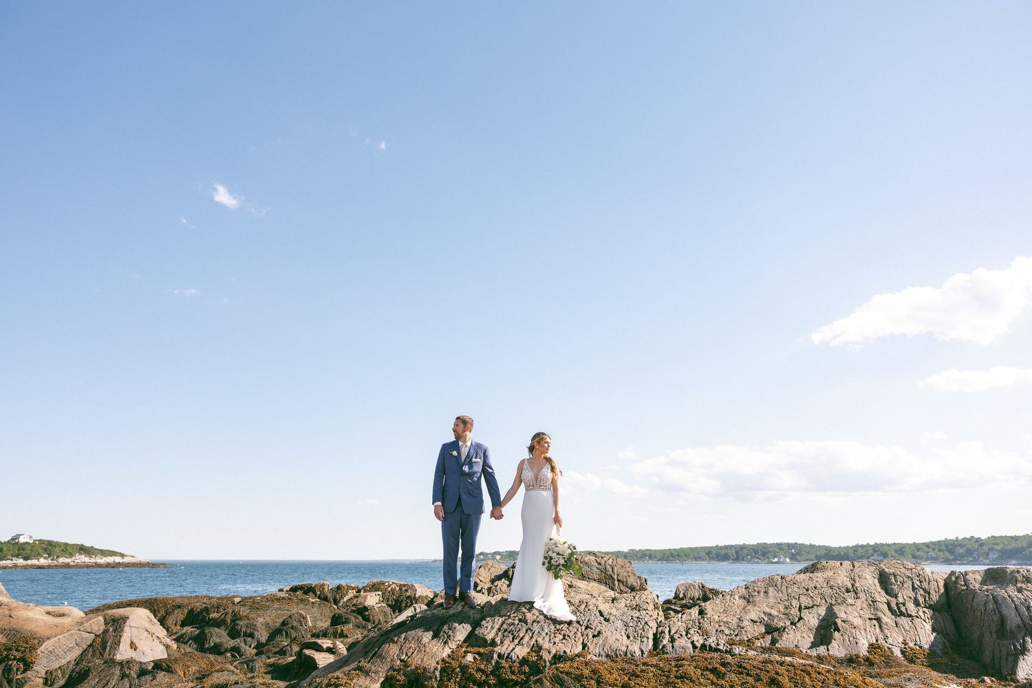 Wedding couple walks hand in hand through a field of yellow wildflowers.