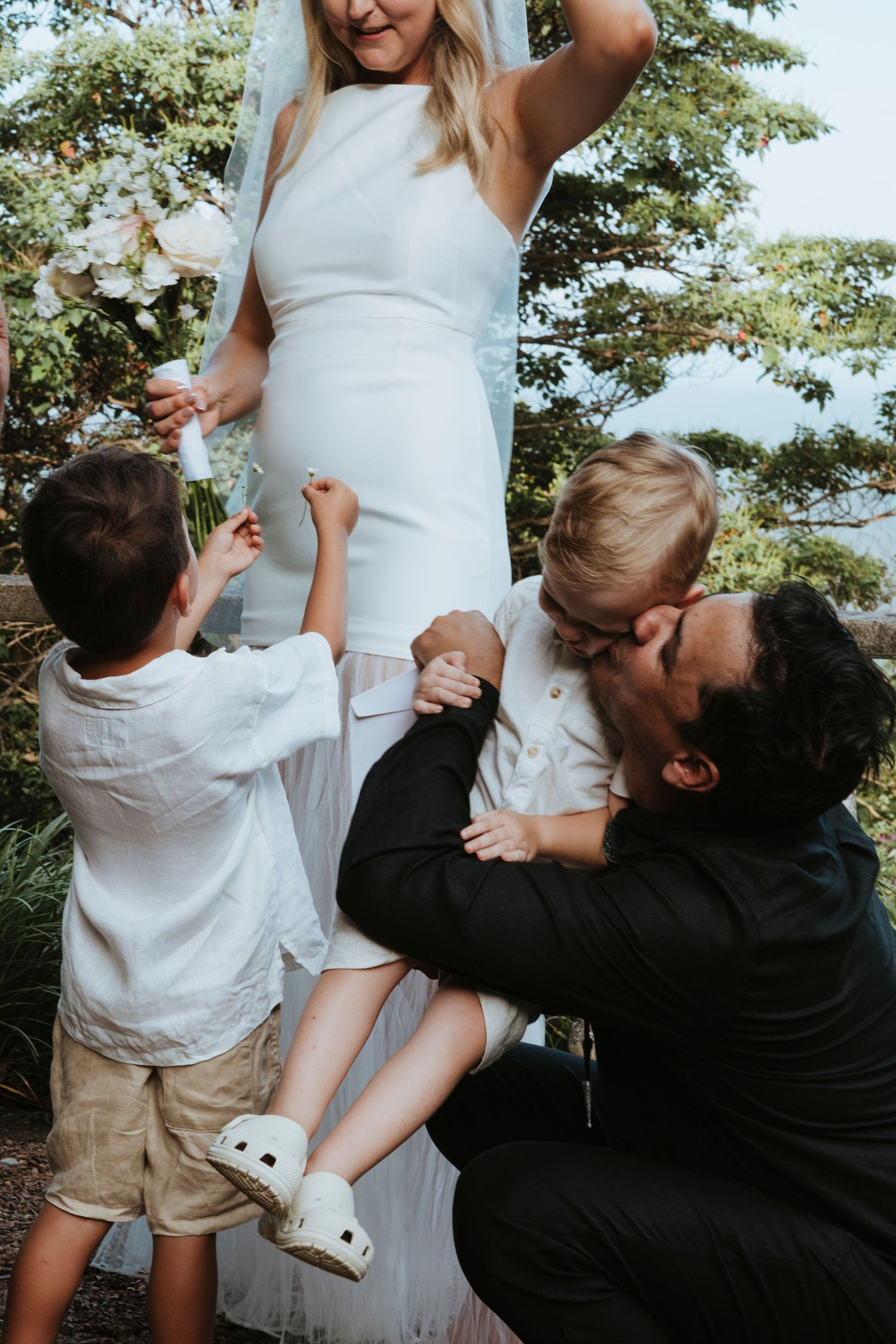 Bridal party throwing confetti in celebration on a grassy hill during golden hour.