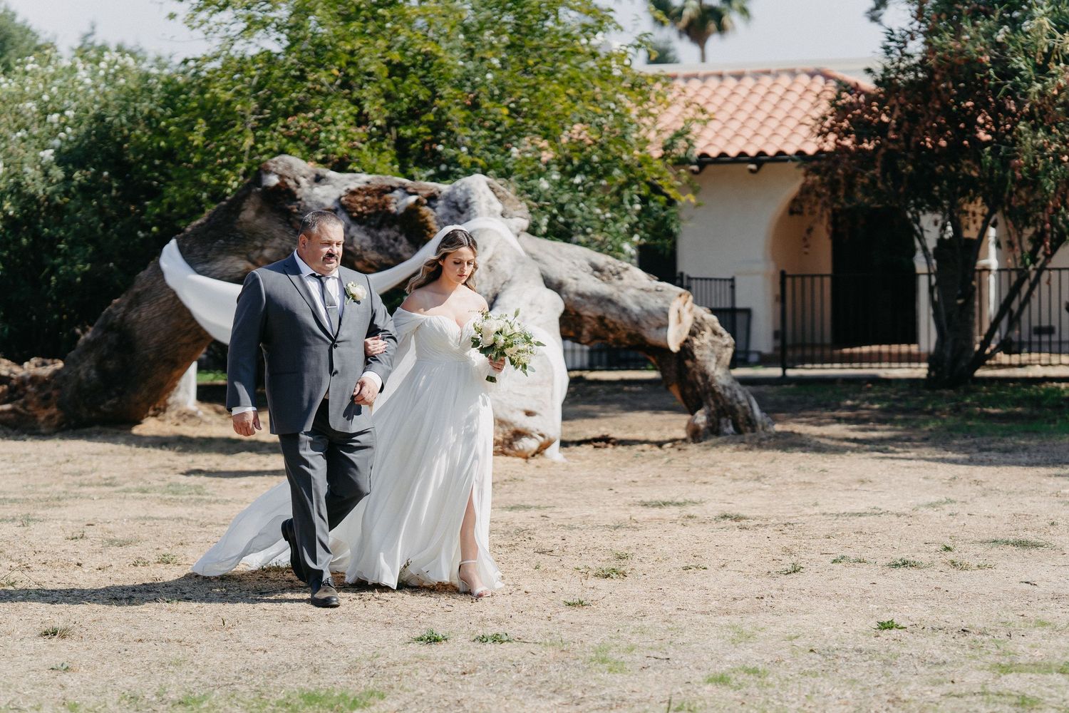 Outdoor wedding celebration with Spanish-style architecture in background.