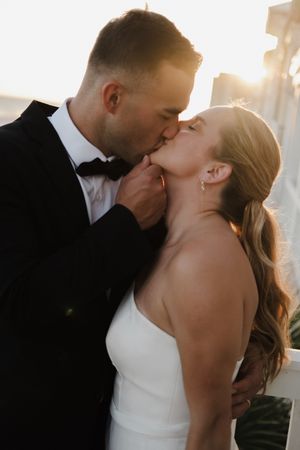 Romantic silhouettes of newlyweds sharing intimate kisses in a bright indoor setting.