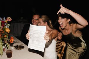 Wedding reception guests laughing and celebrating at a dimly lit venue.