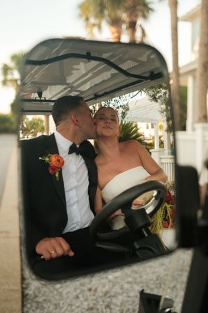 Romantic moment captured through a car window with palm trees in background.