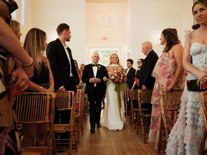 Wedding ceremony guests seated in wooden chairs inside an elegant venue.