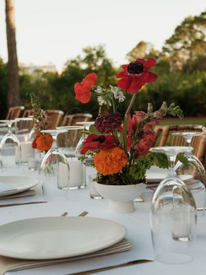 Elegant table settings with colorful floral centerpieces featuring red and orange blooms.