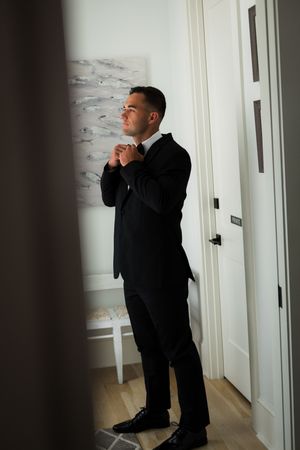 Candid sequence of someone adjusting their formal attire in a bright hallway.