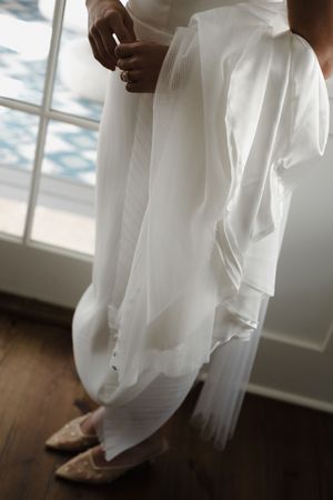 Detail shots of flowing white wedding dress fabric and shoes.