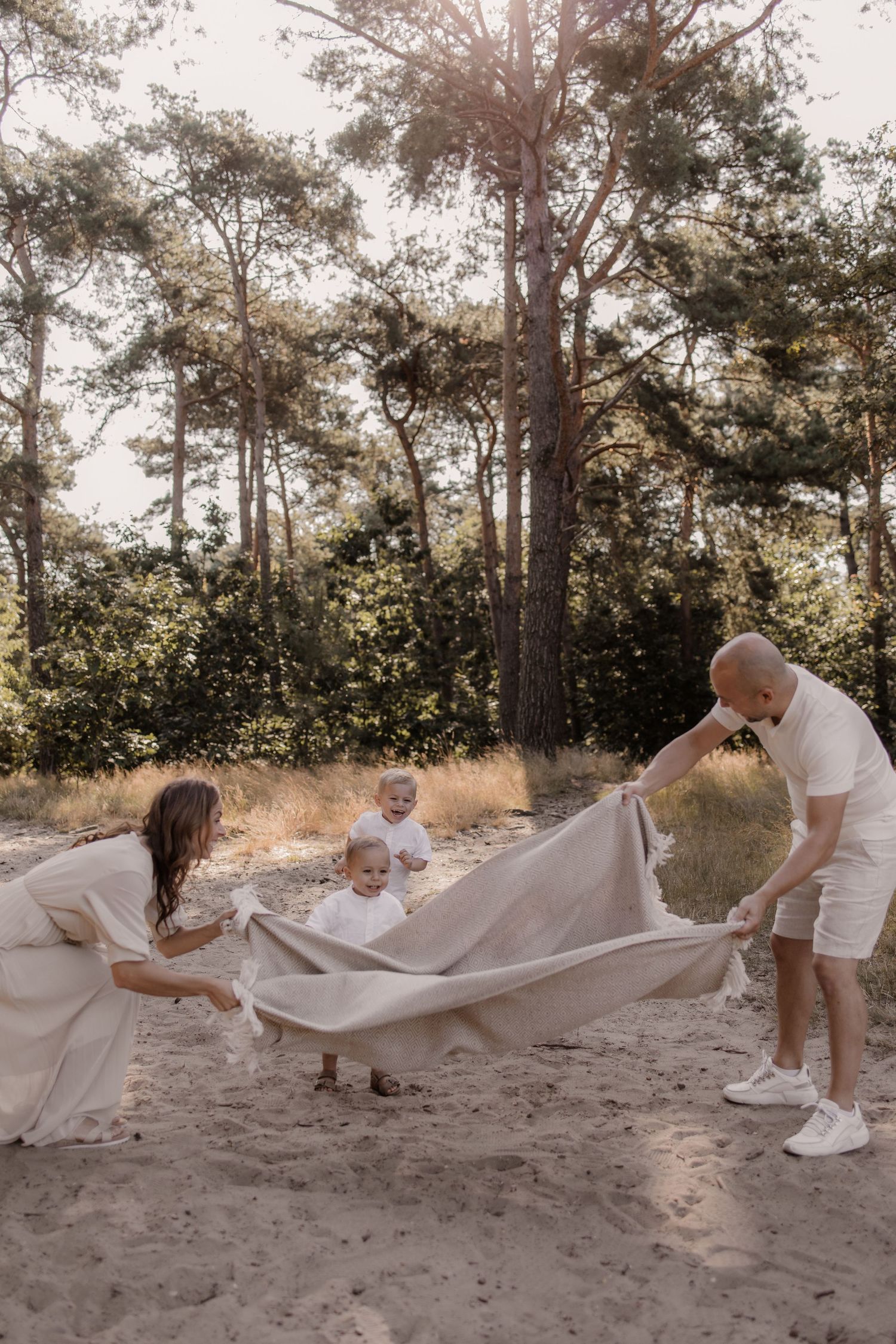 Spelenderwijs gefotografeerd moment tussen ouders en kinderen in het bos.