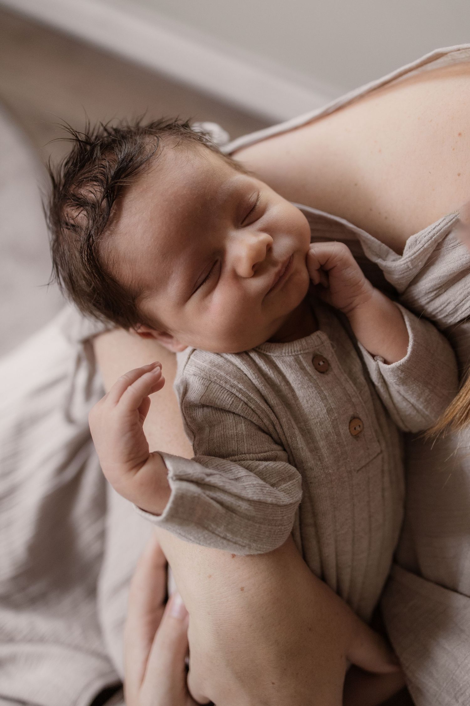 Pasgeboren baby in de armen van moeder tijdens lifestyle shoot thuis