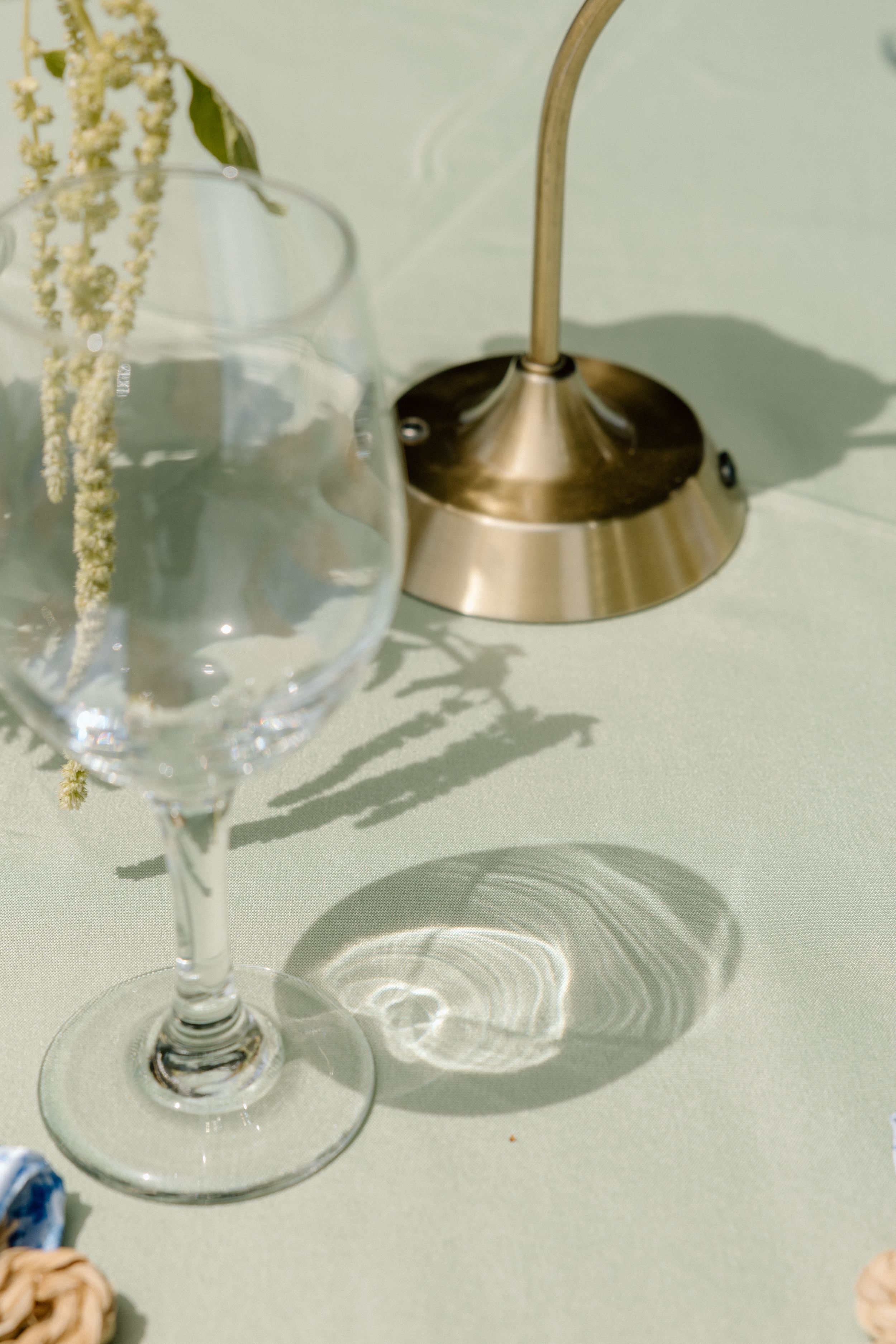 Crystal wine glass casts elegant shadows on white surface beneath pendant lighting fixture.
