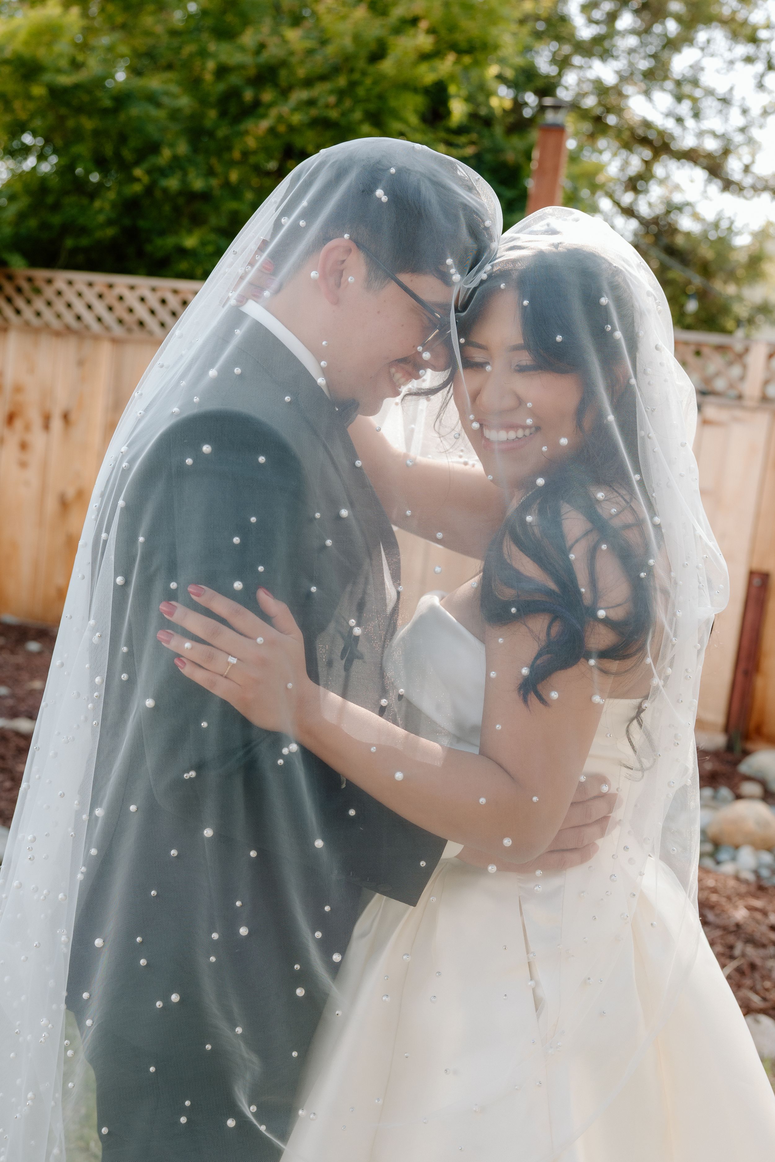 A sequence of wedding photos showing a romantic moment under a flowing white veil in an outdoor garden setting.
