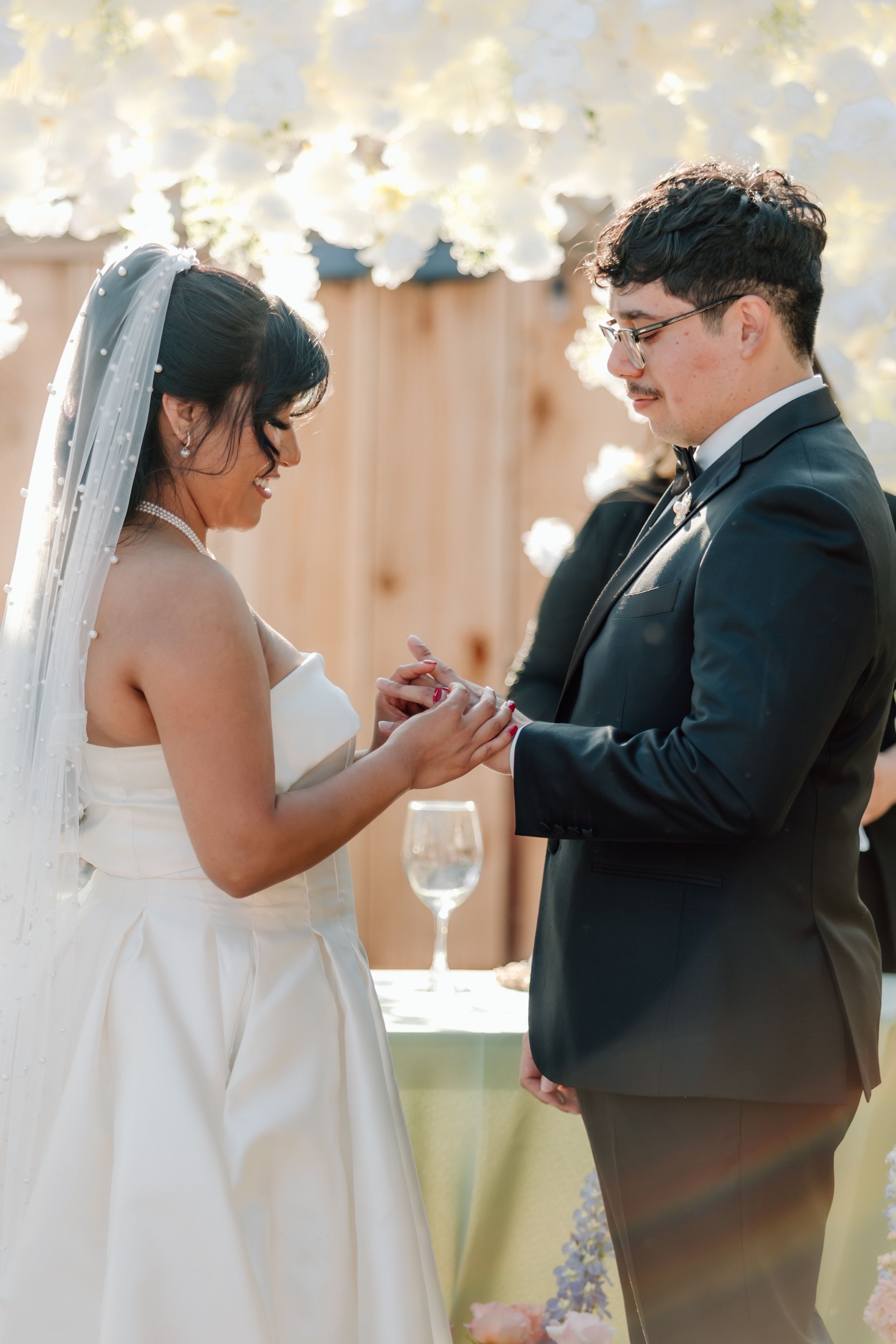A heartfelt wedding ceremony moment as a couple exchanges rings under soft decorative lighting.