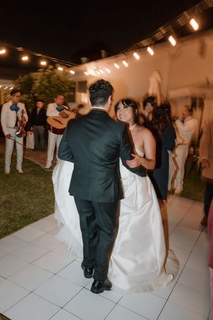Couples dancing together at an indoor-outdoor wedding reception with string lights and white dance floor tiles.