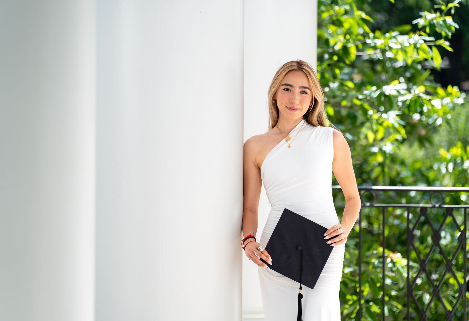 Professional outdoor portrait session setup with white columns and green foliage in background.