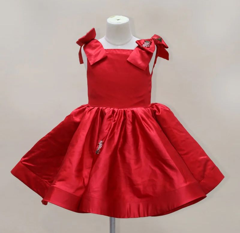 A bright red satin dress with a full gathered skirt and bow details on the shoulders sits on a dress form display.
