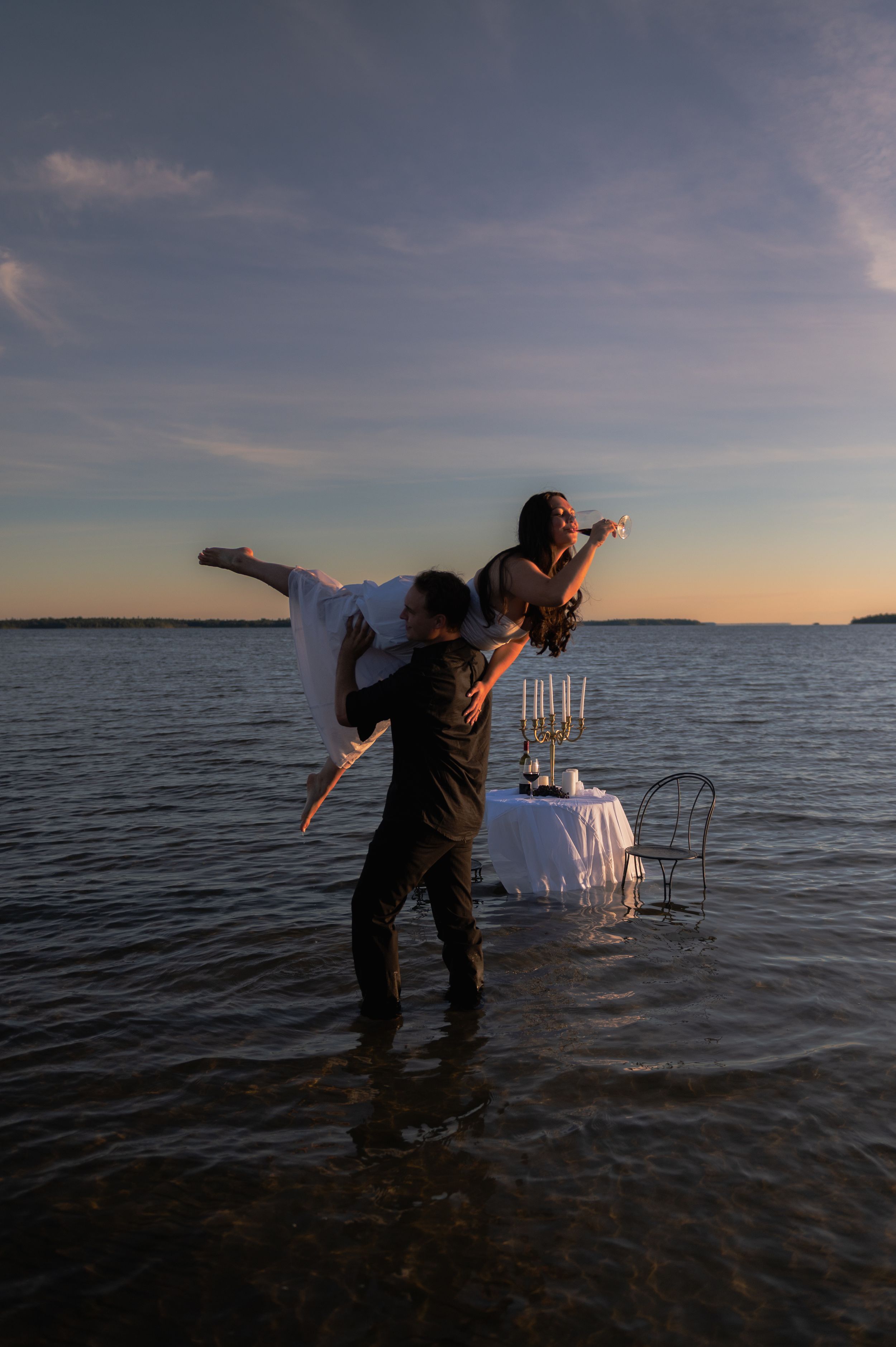 Photographers capturing sunset photos in shallow ocean waters.
