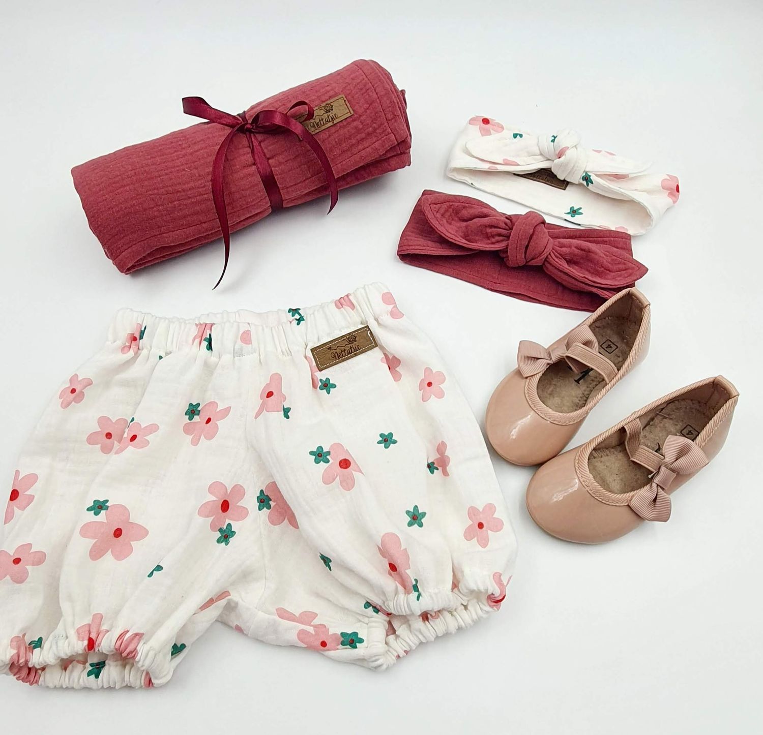 Baby outfit set with floral bloomers, red headband, and beige ballet shoes.