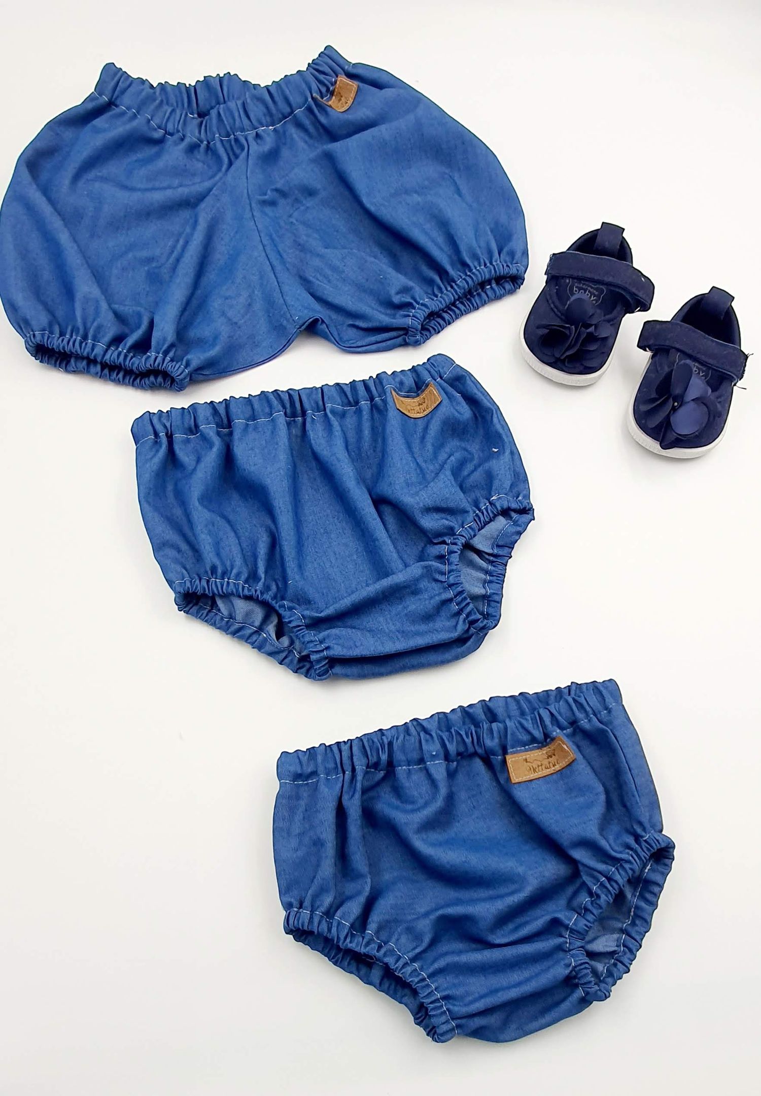 Set of three denim blue baby bloomers with matching navy shoes.