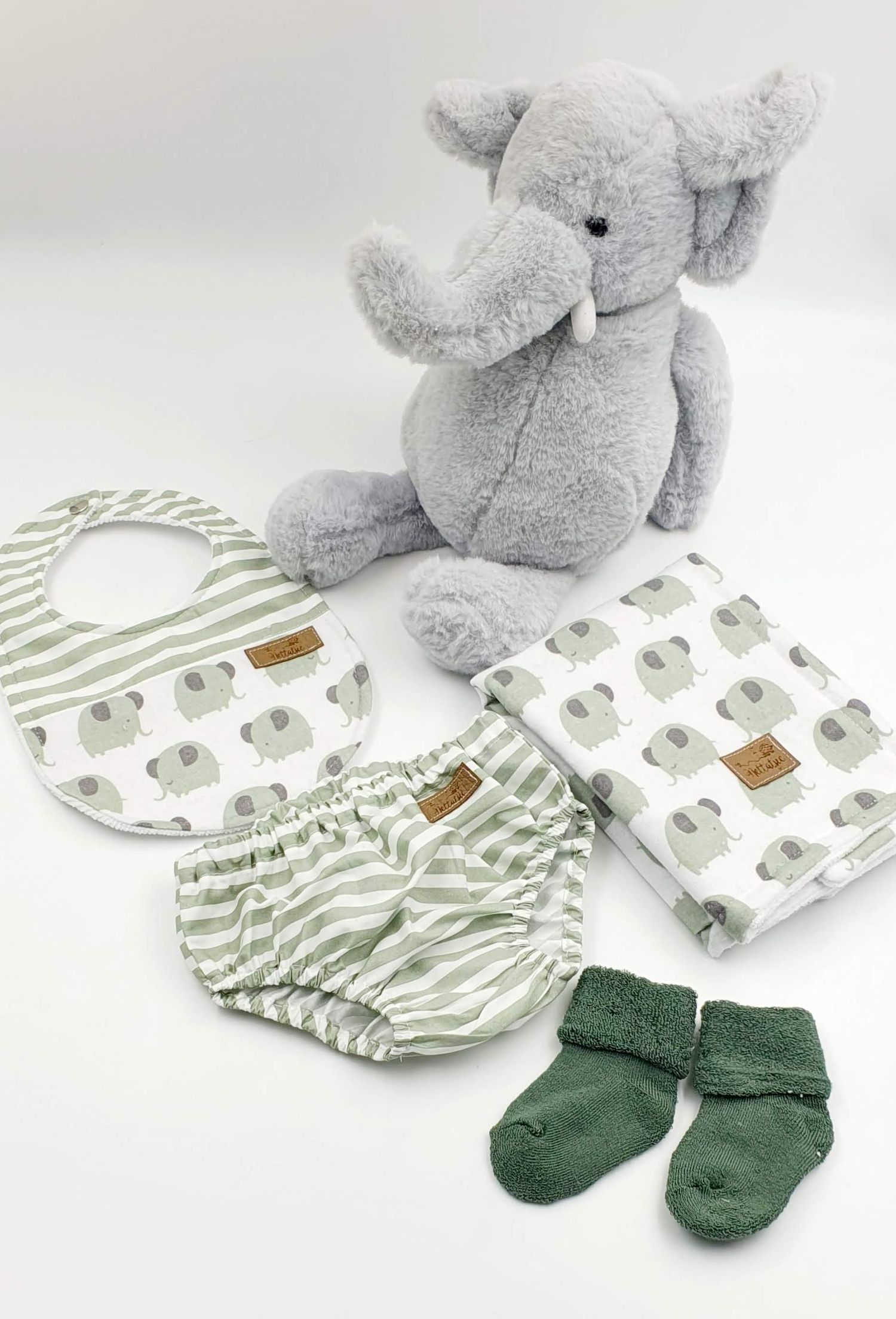 Gray elephant plush toy with matching elephant print baby accessories and green socks.
