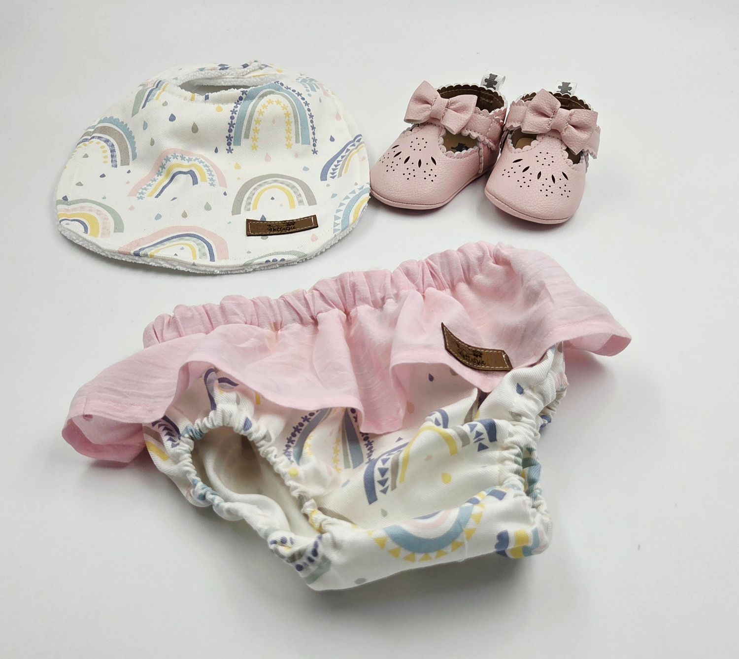 Rainbow print baby accessories set with pink bloomers and matching shoes.