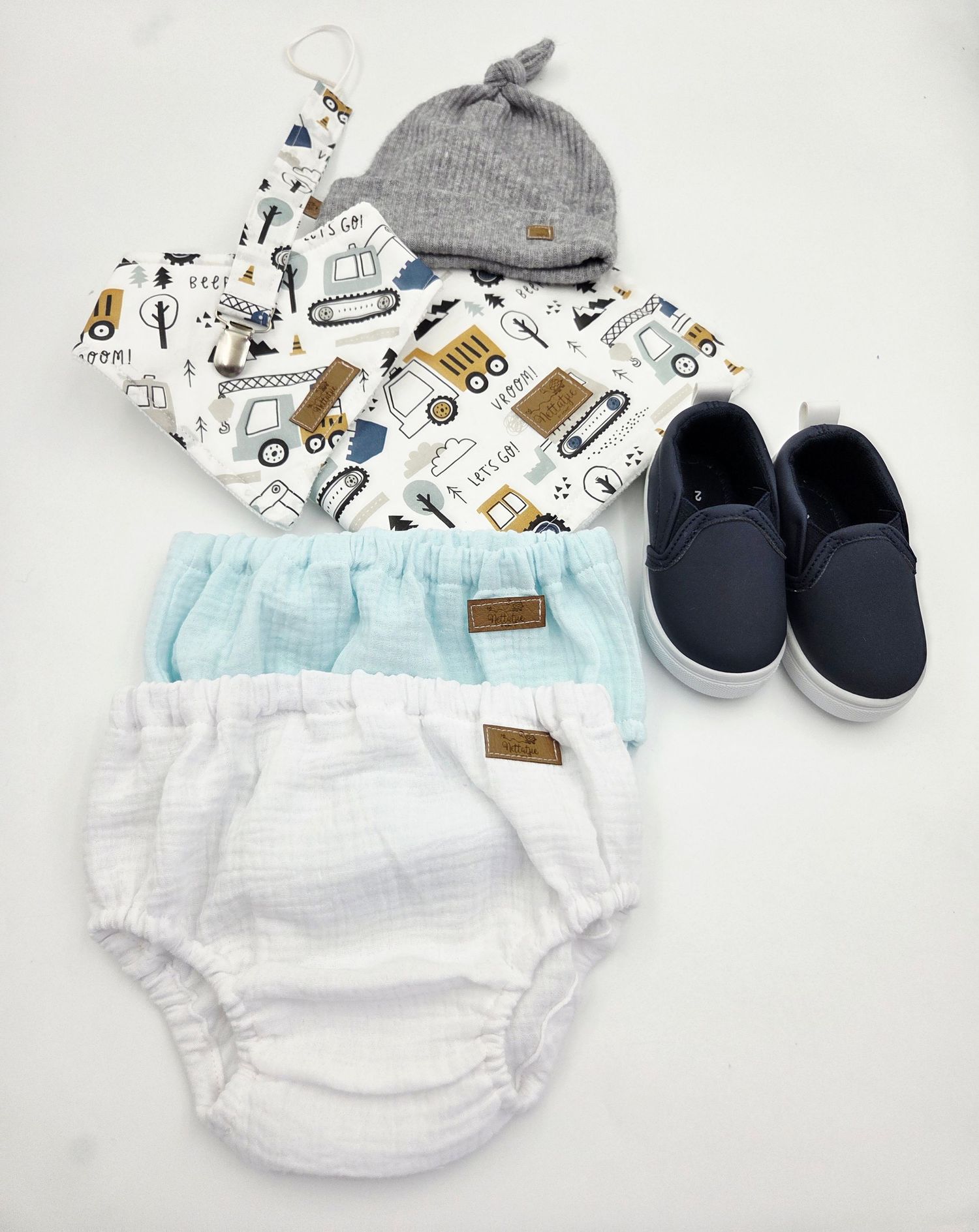 White baby bloomers with graphic print accessories and navy shoes on display.