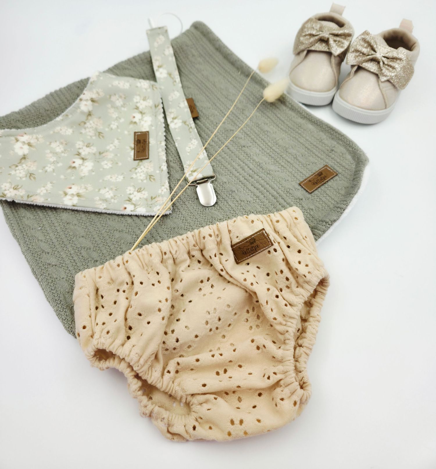 Sage green and beige baby bloomers with eyelet detail and matching shoes.