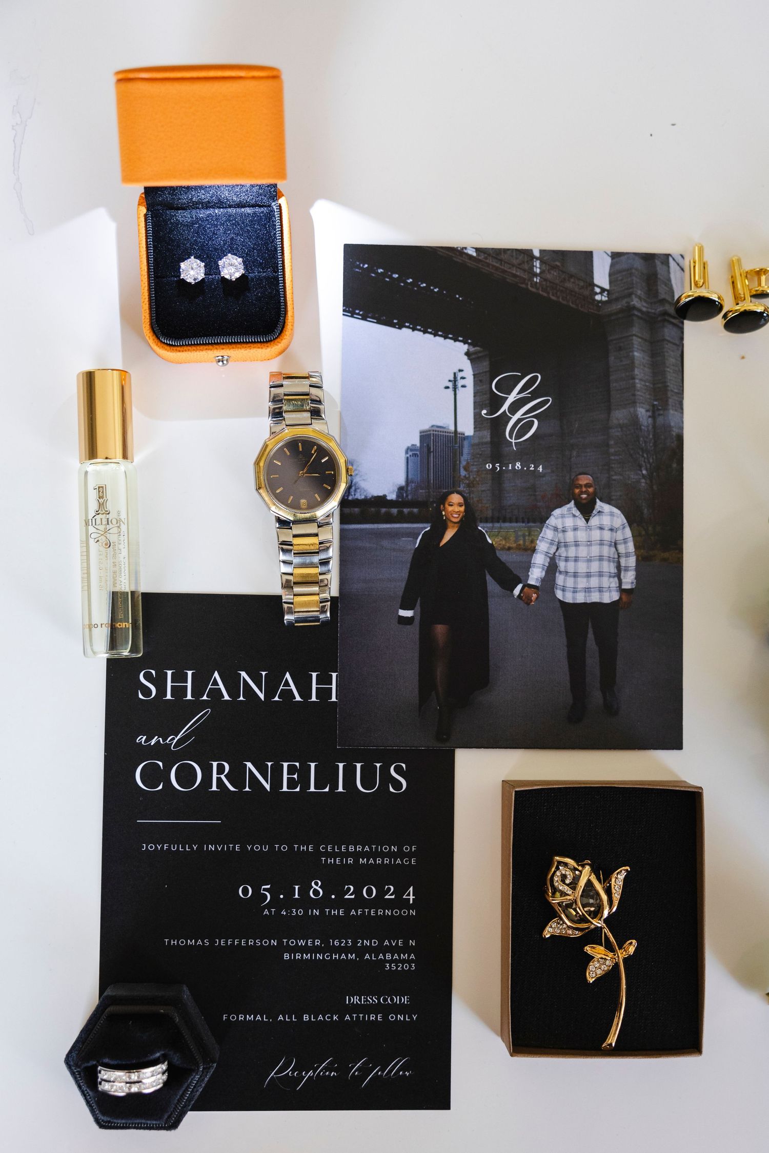 Wedding invitation and details flatlay featuring jewelry, perfume and a black and white engagement photo.