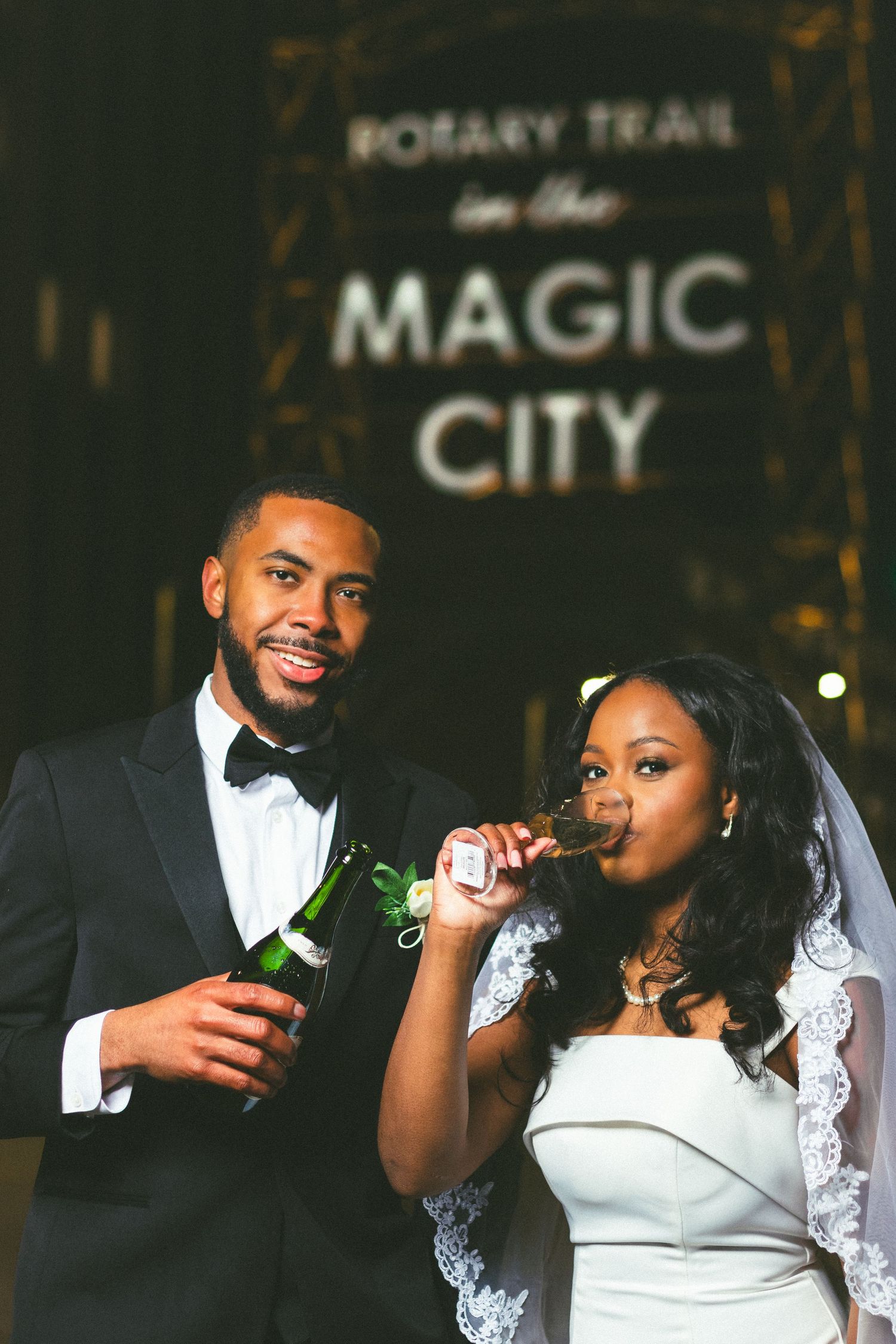 A couple celebrates with drinks under the Magic City sign on their wedding night.