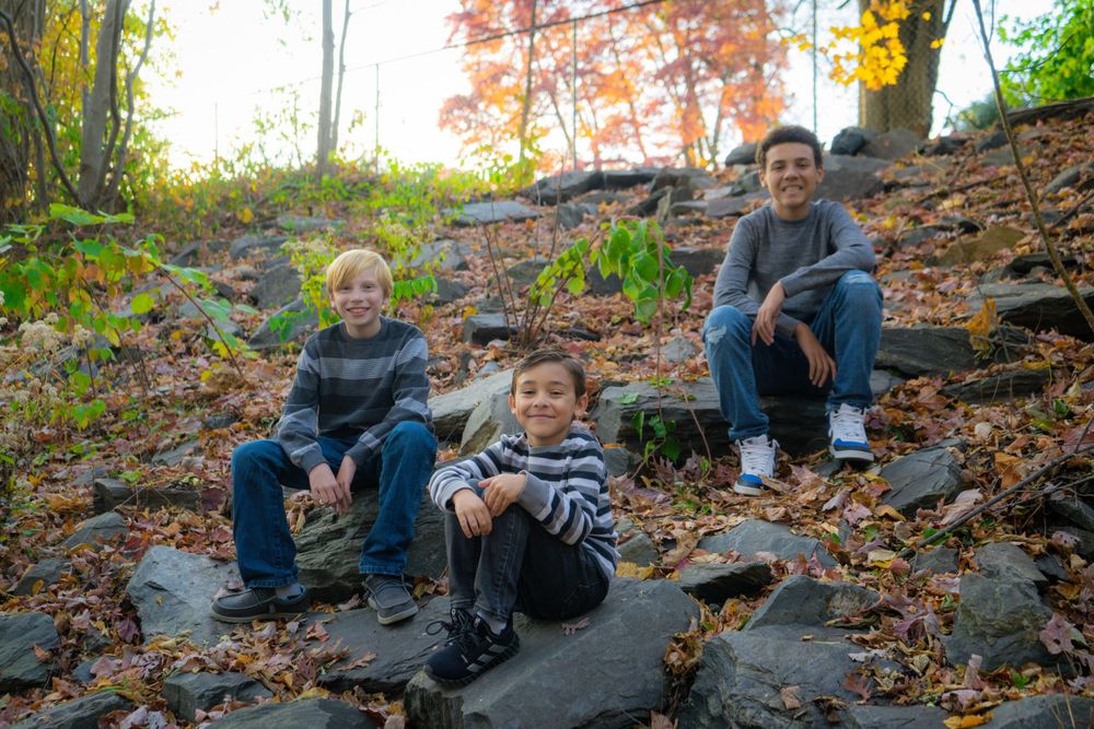 Children sitting on stone steps covered in fallen autumn leaves.