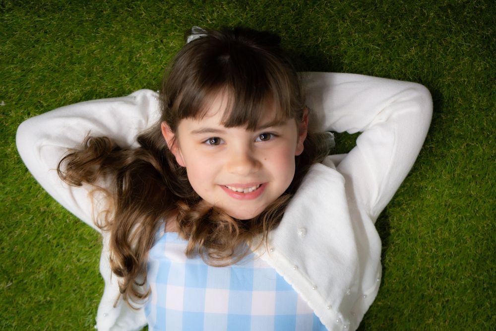 A series of candid photos showing someone lying on green grass wearing a white sweater.