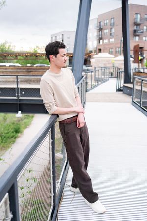 Four artistic fashion photos showing a person in a beige sweater and brown pants posing on an urban rooftop balcony.