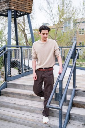 A series of fashion photos showing a casual outfit with beige shirt and brown pants on concrete steps with metal railings.