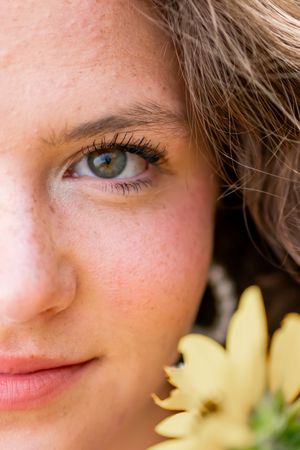 A stunning macro portrait showing bright blue eyes and natural beauty next to a sunflower.