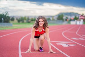 Runner in starting position on red track ready to sprint.