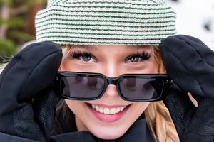 Green and white striped knit hat worn outdoors with dark sunglasses on a sunny day.