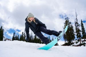 Snowboarder performs series of jumping tricks at ski resort under blue cloudy sky.
