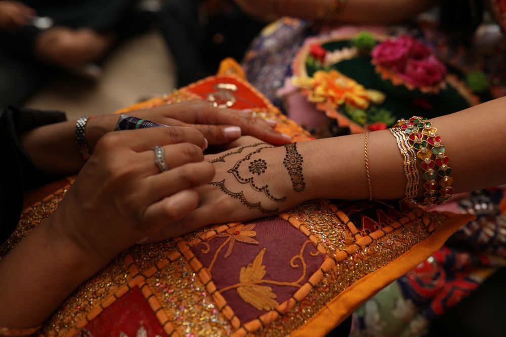 Close-up of hands applying traditional henna design during an Indian wedding ceremony.