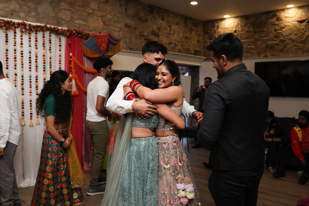Wedding celebration with dancing and embracing in an indoor stone-walled venue.