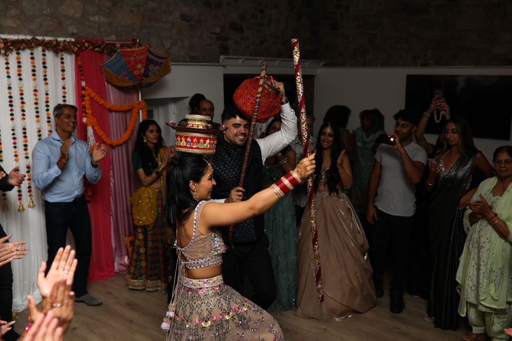 Guests cheer as dancers perform during a festive wedding celebration in a decorated indoor venue.