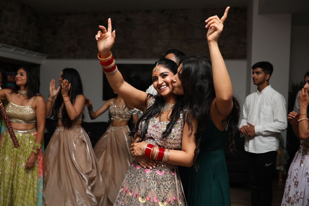 Wedding guest dances with raised arms during indoor celebration wearing traditional Indian attire.